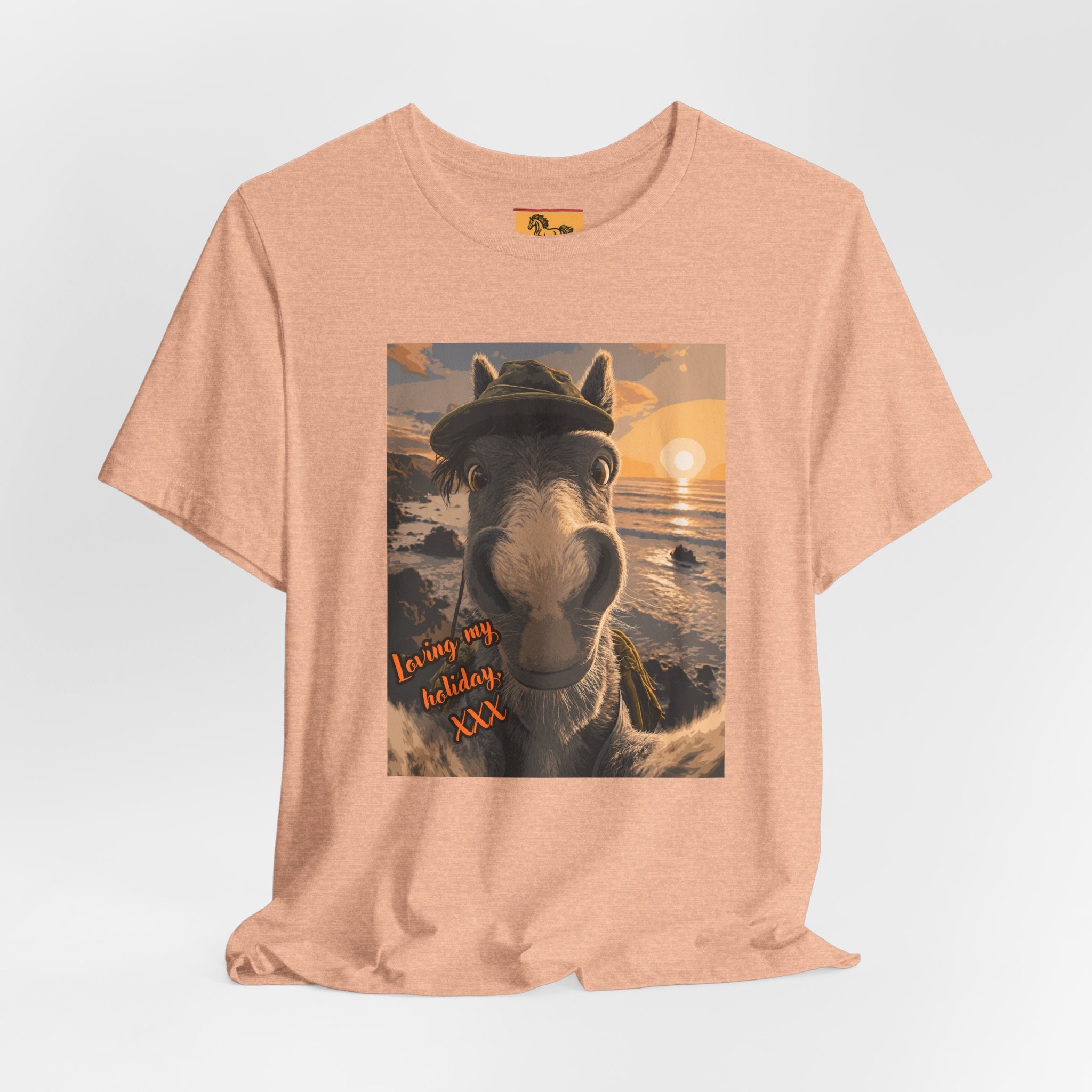 A Bella + Canvas 3001 unisex t-shirt featuring an illustrated horse taking a beach selfie at sunset, wearing a hat, with the words 'Loving my holiday XXX' in orange script. 