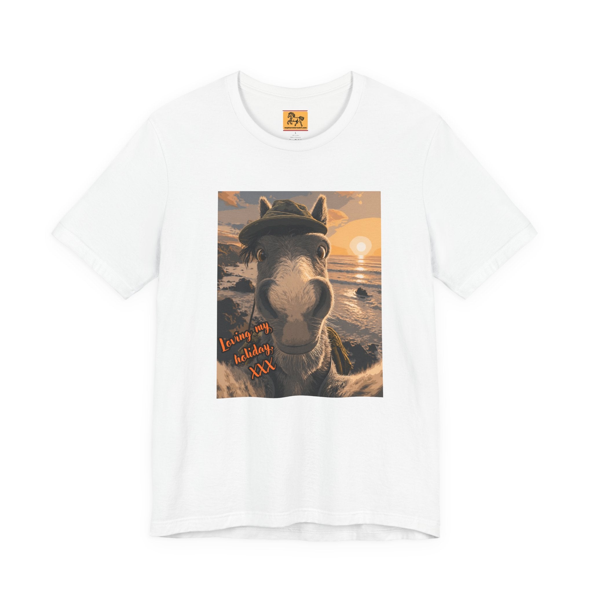 A white Bella + Canvas 3001 unisex t-shirt featuring an illustrated horse taking a beach selfie at sunset, wearing a hat, with the words 'Loving my holiday XXX' in orange script. 