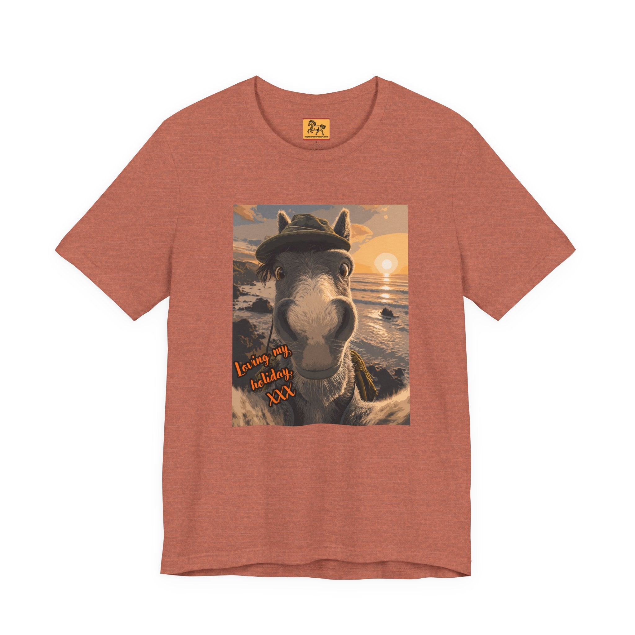 A rust Bella + Canvas 3001 unisex t-shirt featuring an illustrated horse taking a beach selfie at sunset, wearing a hat, with the words 'Loving my holiday XXX' in orange script. 