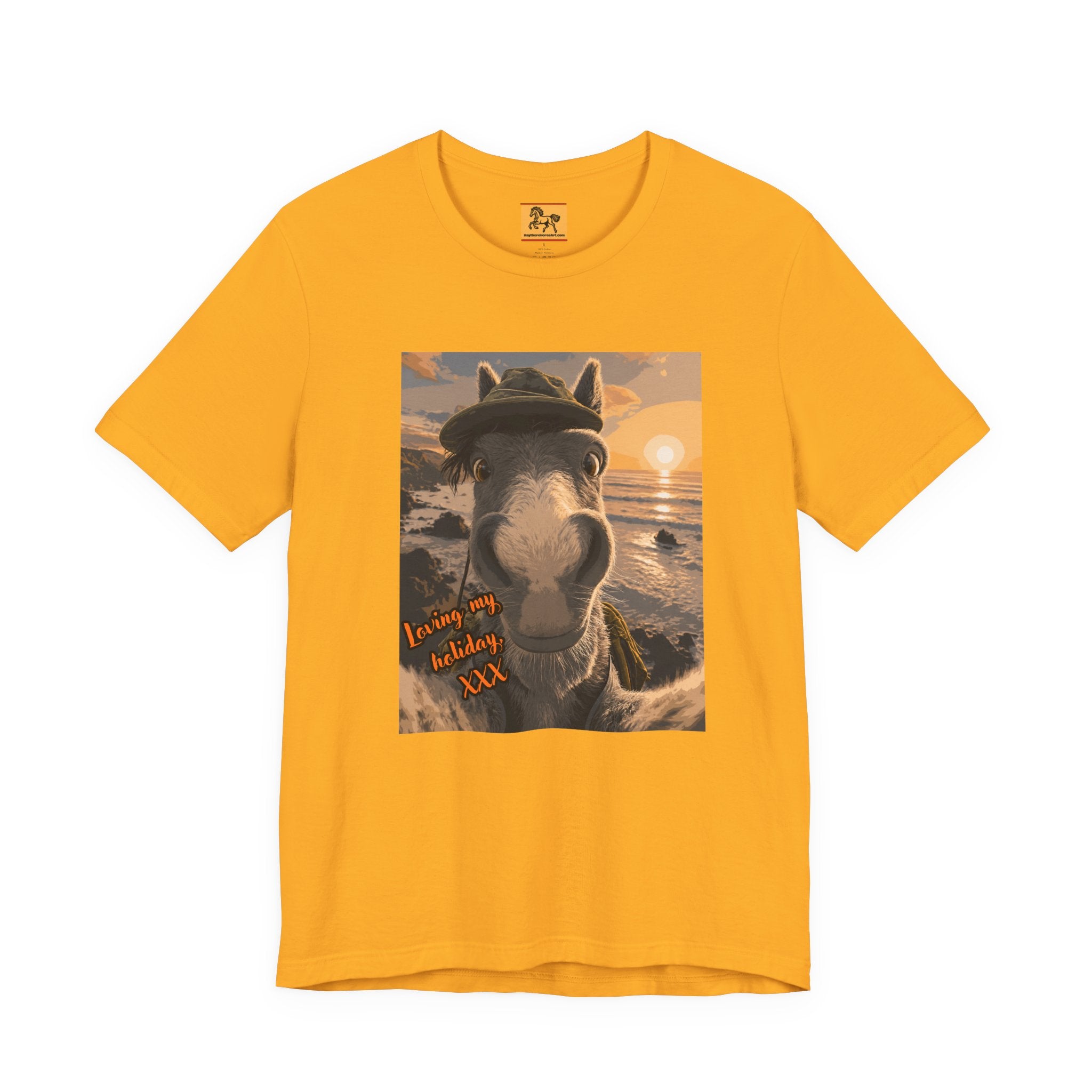 A gold Bella + Canvas 3001 unisex t-shirt featuring an illustrated horse taking a beach selfie at sunset, wearing a hat, with the words 'Loving my holiday XXX' in orange script. 