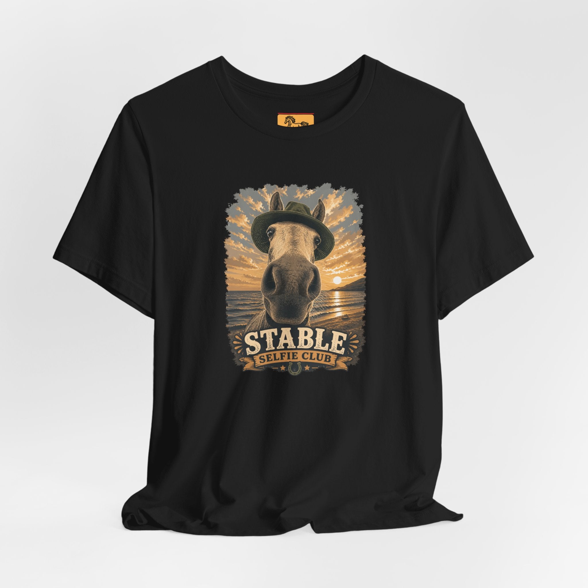 Stable Selfie Club unisex t-shirt in black, featuring original equestrian artwork of a horse wearing a hat taking a selfie at sunset on a beach, printed on Bella & Canvas 3001 tee by Hay there Horse Art.