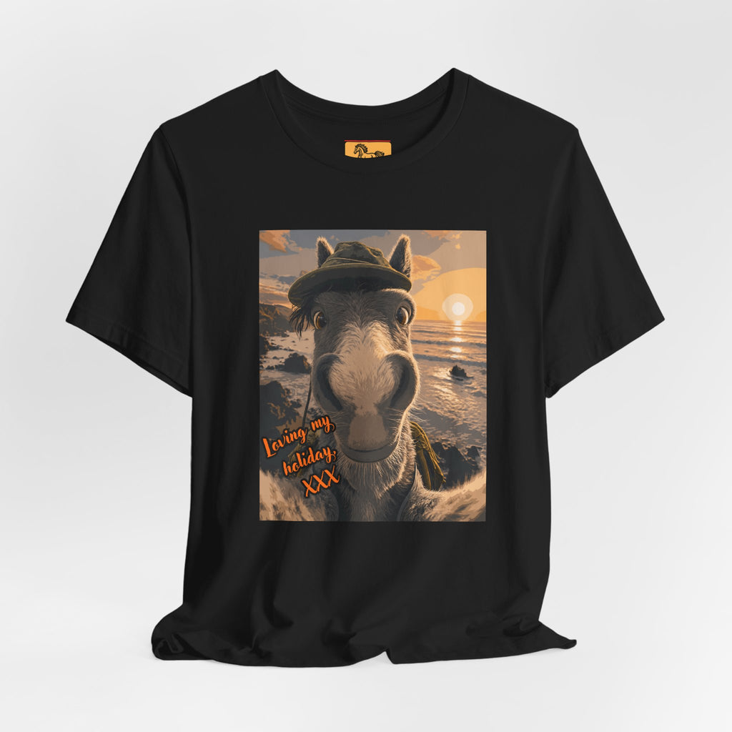 A Bella + Canvas 3001 unisex t-shirt featuring an illustrated horse taking a beach selfie at sunset, wearing a hat, with the words 'Loving my holiday XXX' in orange script. 