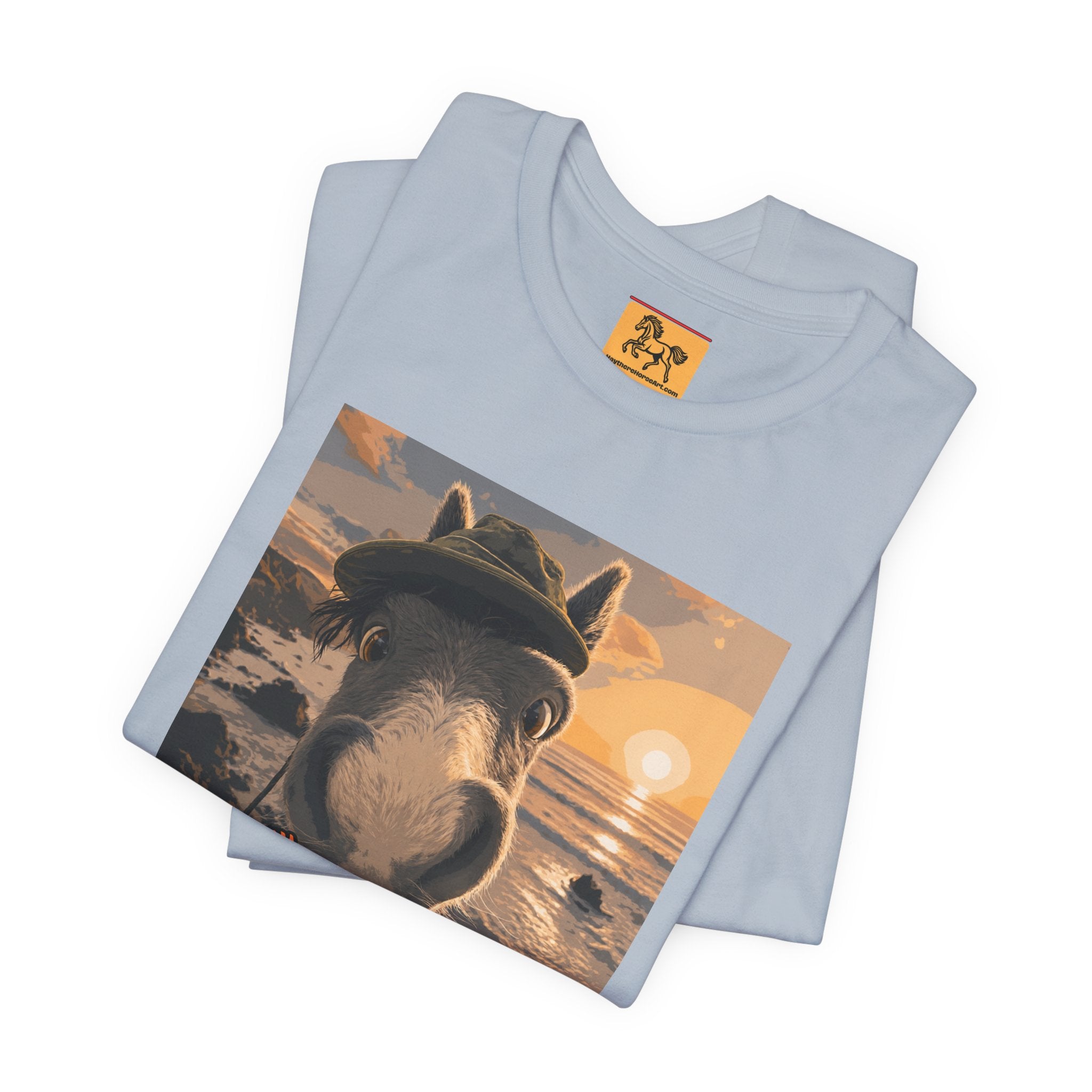 A Bella + Canvas 3001 unisex t-shirt featuring an illustrated horse taking a beach selfie at sunset, wearing a hat, with the words 'Loving my holiday XXX' in orange script. 