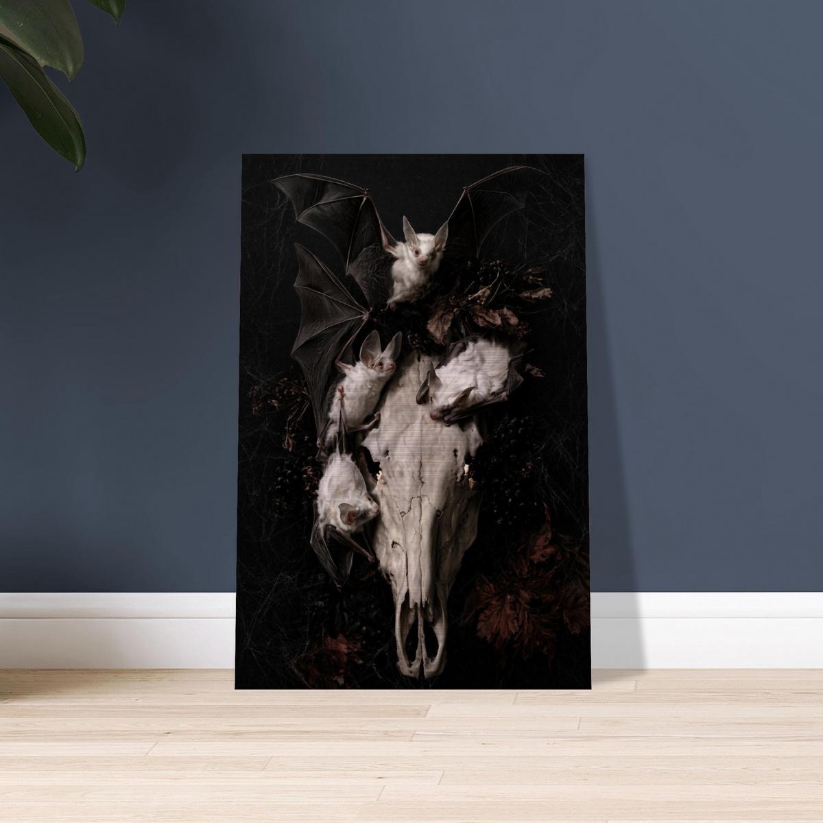 Gothic vanitas metal wall art print of three albino bats and a weathered horse skull with glowing eye sockets, surrounded by dried botanicals and cobwebs on a black background, Dutch Golden Age still life style, brushed aluminum print