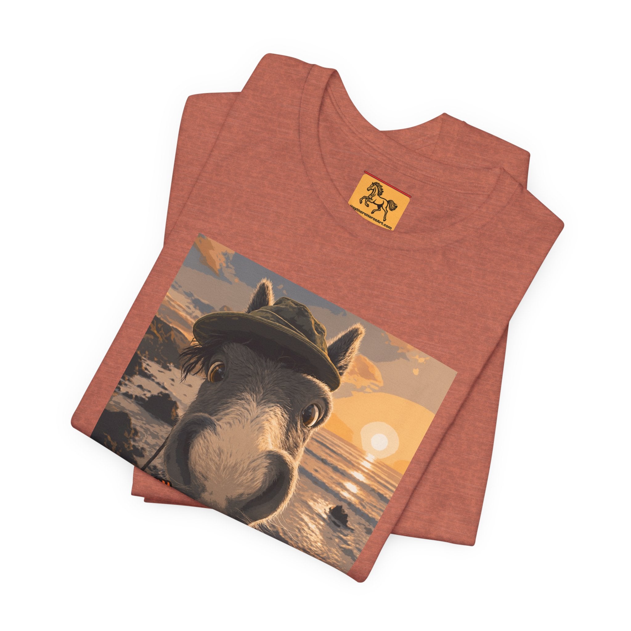 A Bella + Canvas 3001 unisex t-shirt featuring an illustrated horse taking a beach selfie at sunset, wearing a hat, with the words 'Loving my holiday XXX' in orange script. 