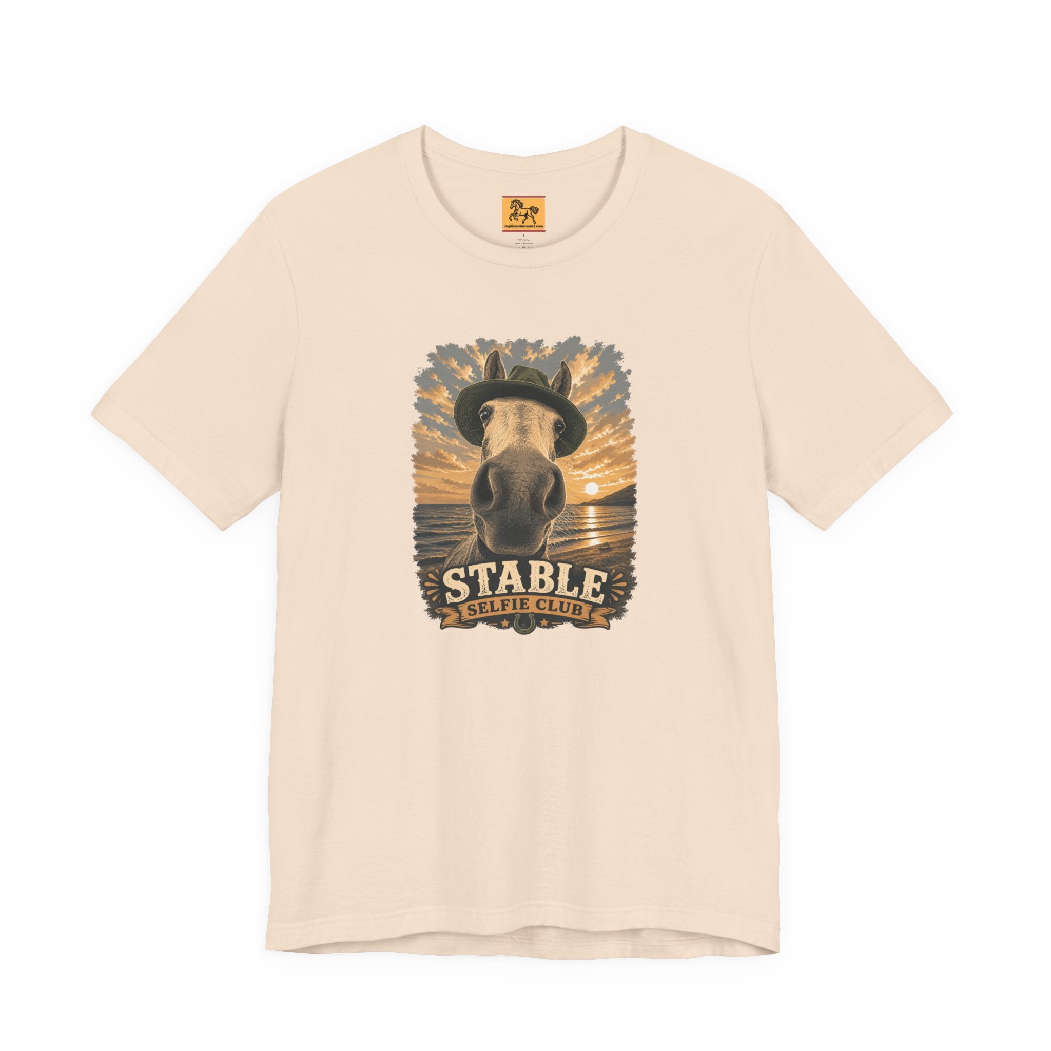 Stable Selfie Club unisex t-shirt in soft cream, featuring original equestrian artwork of a horse wearing a hat taking a selfie at sunset on a beach, printed on Bella & Canvas 3001 tee by Hay there Horse Art.