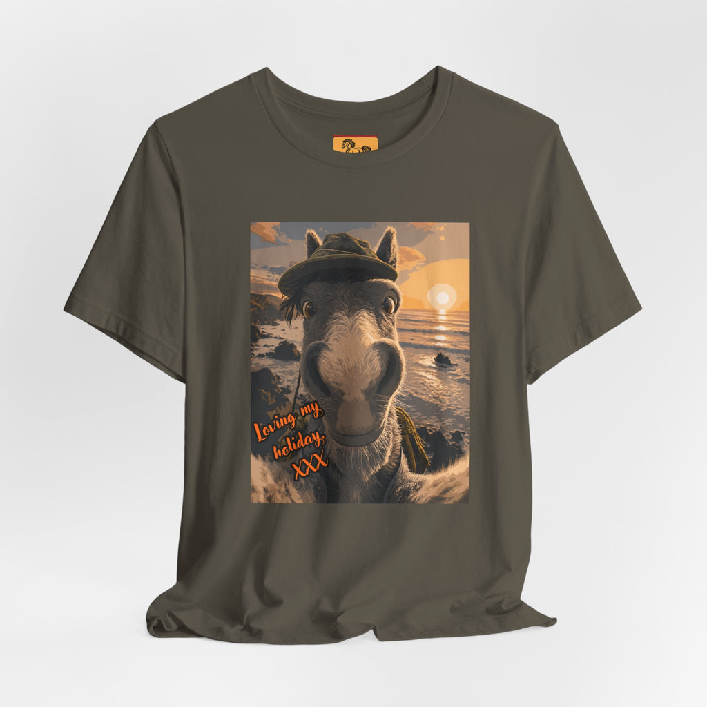 A Bella + Canvas 3001 unisex t-shirt featuring an illustrated horse taking a beach selfie at sunset, wearing a hat, with the words 'Loving my holiday XXX' in orange script. 