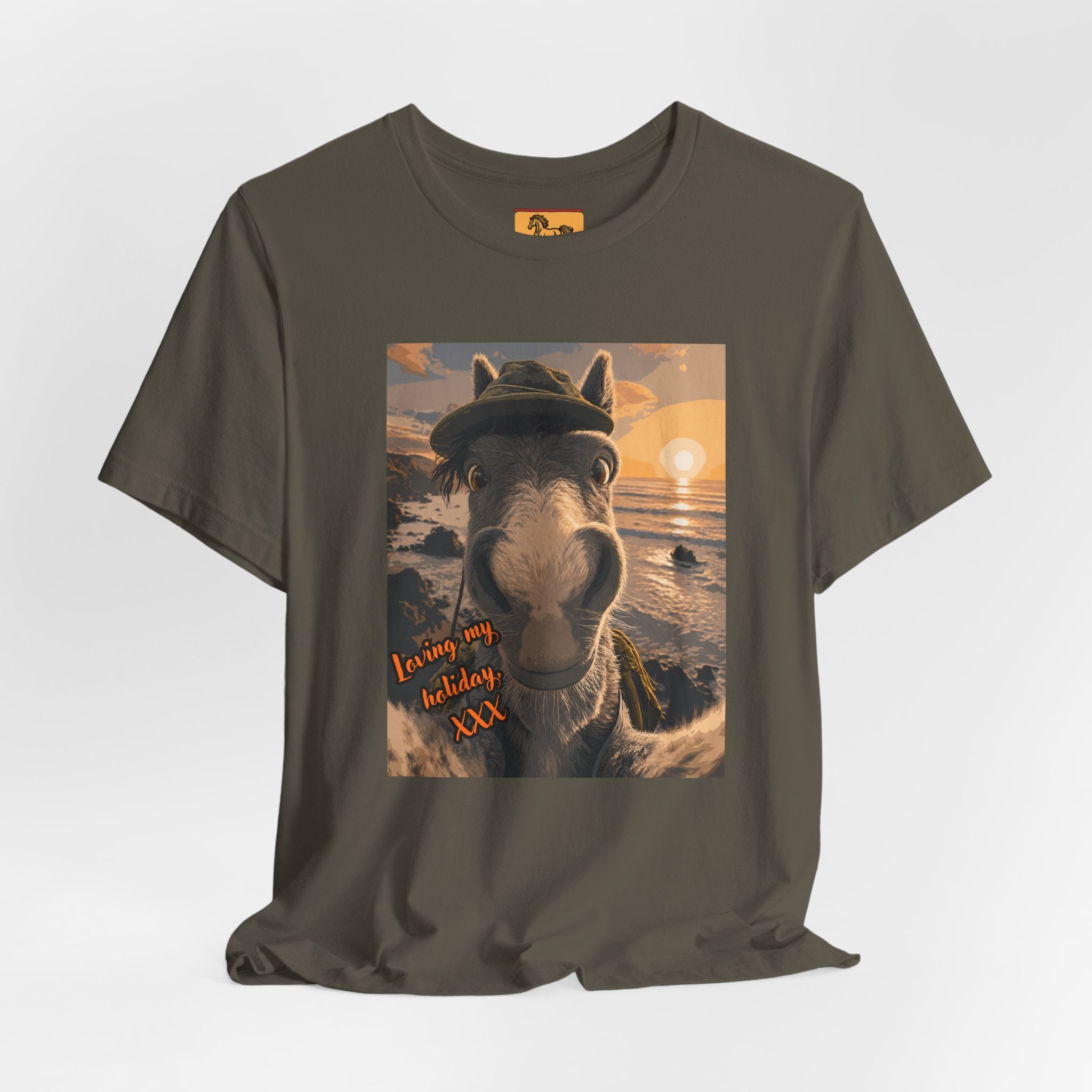 A Bella + Canvas 3001 unisex t-shirt featuring an illustrated horse taking a beach selfie at sunset, wearing a hat, with the words 'Loving my holiday XXX' in orange script. 