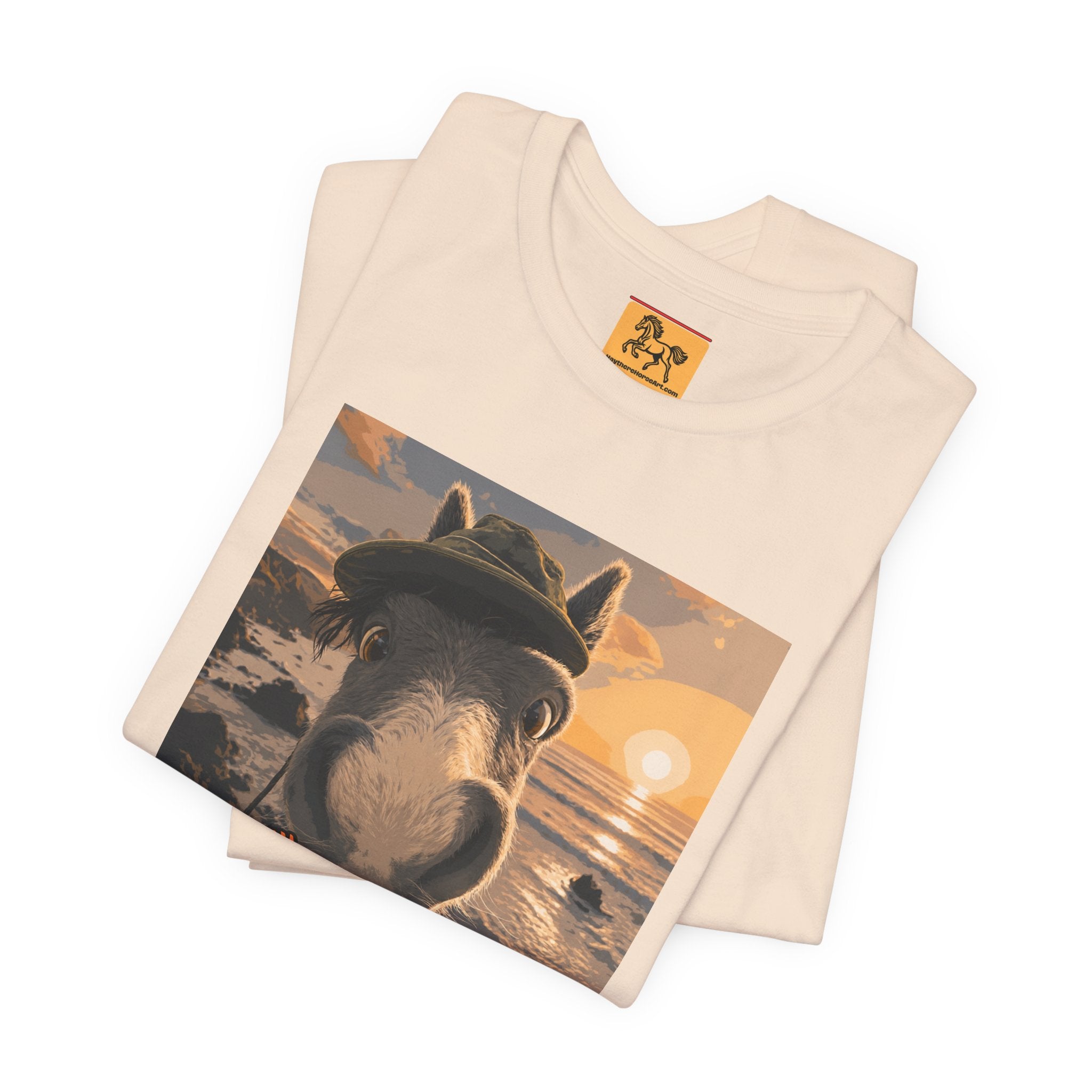 A Bella + Canvas 3001 unisex t-shirt featuring an illustrated horse taking a beach selfie at sunset, wearing a hat, with the words 'Loving my holiday XXX' in orange script. 