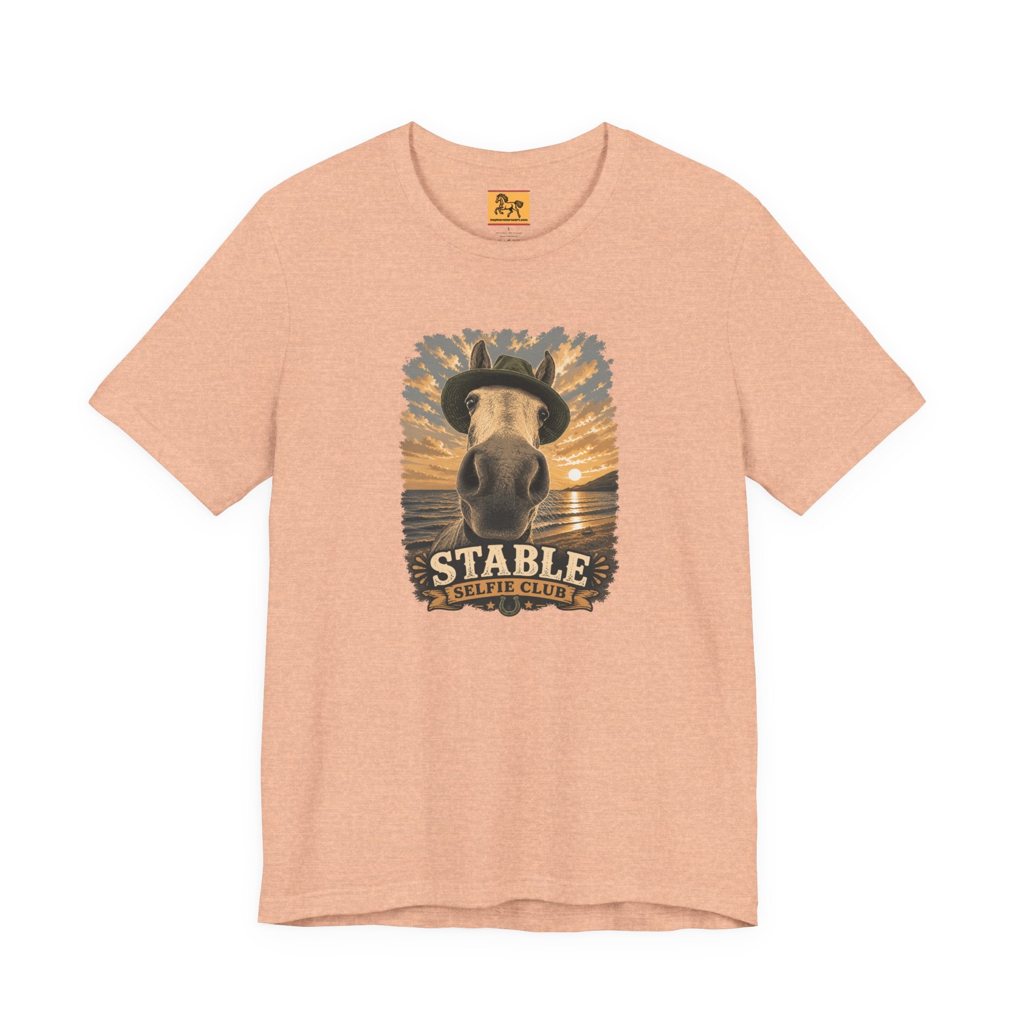 Stable Selfie Club unisex t-shirt in heather peach, featuring original equestrian artwork of a horse wearing a hat taking a selfie at sunset on a beach, printed on Bella & Canvas 3001 tee by Hay there Horse Art.